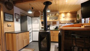 Cucina con mobili in legno, piano cottura integrato, frigorifero e zona bar con sgabelli.
