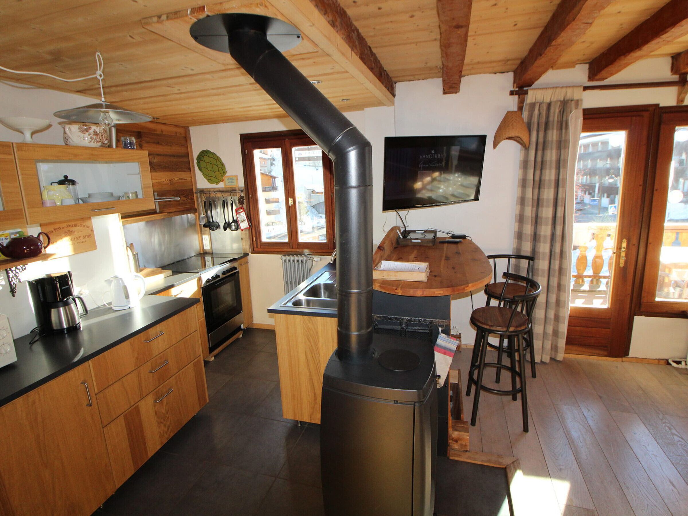 Una cucina con mobili in legno, un fornello e un televisore montato a parete.