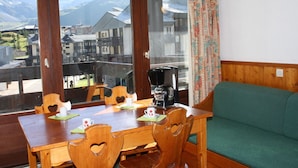 A dining area with a wooden table, heart-shaped chairs, and a green sofa. - Cozy studio 4 ppl, south balcony, Tignes center (Tignes-Le Lavachet)
