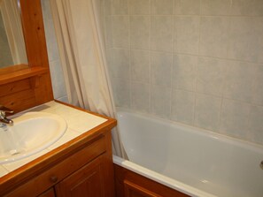 Une salle de bain avec un meuble-lavabo en bois, un évier et une baignoire.