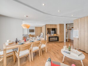 Una sala de estar moderna con una mesa de comedor de madera, asientos cómodos, una televisión empotrada y una chimenea.
