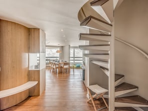 Een modern interieur met een wenteltrap, houten vloer en een eethoek met natuurlijk licht.