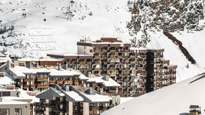 Une ville de montagne enneigée, avec des immeubles modernes à plusieurs étages, dont un hôtel doté de balcons.
