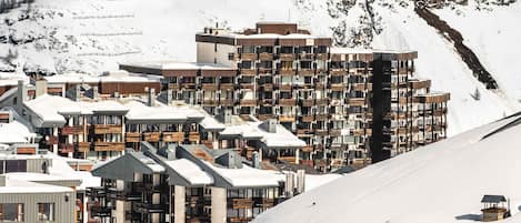 A snow-covered mountain town with modern multi-story buildings, including a hotel with balconies.
