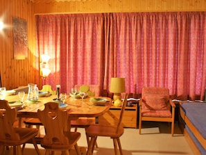 A cozy room with a wooden dining table set for four, a single bed, and a chair.