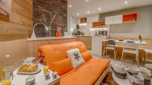 A modern kitchen with a stone wall backsplash, wooden cabinets, and a dining area with a table set for two. - Renovated 1BR 4 pers in Tignes, south balcony (Tignes-Le Lavachet)