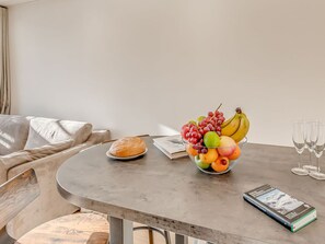Ein Esstisch mit Obstschale, Brotlaib, Buch und Weingläsern.