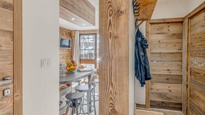 A modern kitchen with wooden accents, a dining area with bar stools, and a view of the outdoors.