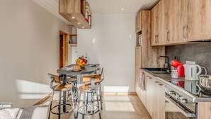 A compact kitchen with wooden cabinets, a central island with stools, and modern appliances.