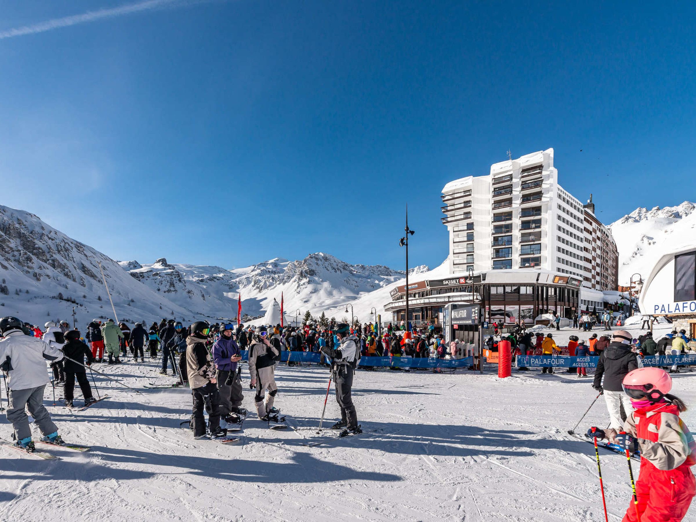 A ski resort with a large building, likely a hotel or resort center, surrounded by snow-covered mountains.