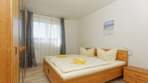 Een keurig opgemaakt slaapkamer met een houten bed, een nachtkastje en een bijzettafeltje.