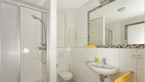 Een badkamer met een douche met glazen wand, een toilet en een wastafel met spiegel.