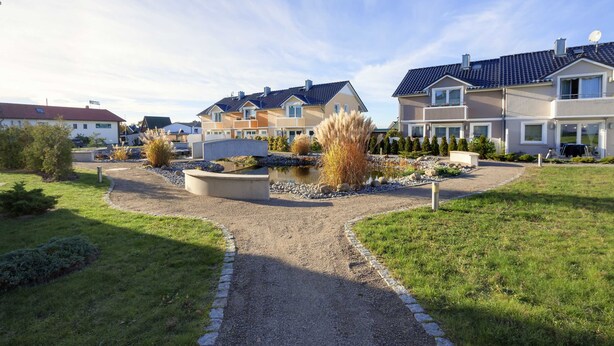 A row of modern two-story houses with a central gravel path and landscaped garden.
