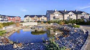 A residential area with modern houses, a small pond, and a bridge.