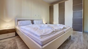 A modern bedroom with a large bed, a nightstand, and a built-in wardrobe.