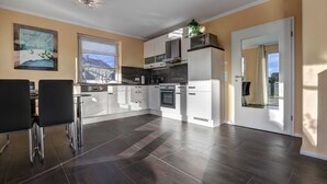A modern kitchen with white cabinets, a built-in oven, and a large window.