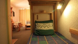 A narrow room with a bed, a wooden table, and a chair. - Cozy Studio 4 pax in Tignes (Tignes-Le Lavachet)