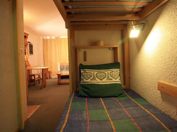 Ein schmales Zimmer mit einem Bett, einem Holztisch und einem Stuhl.