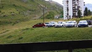 A parking lot with cars, a building, and a grassy hillside. - Cozy Studio 4 pax in Tignes (Tignes-Le Lavachet)