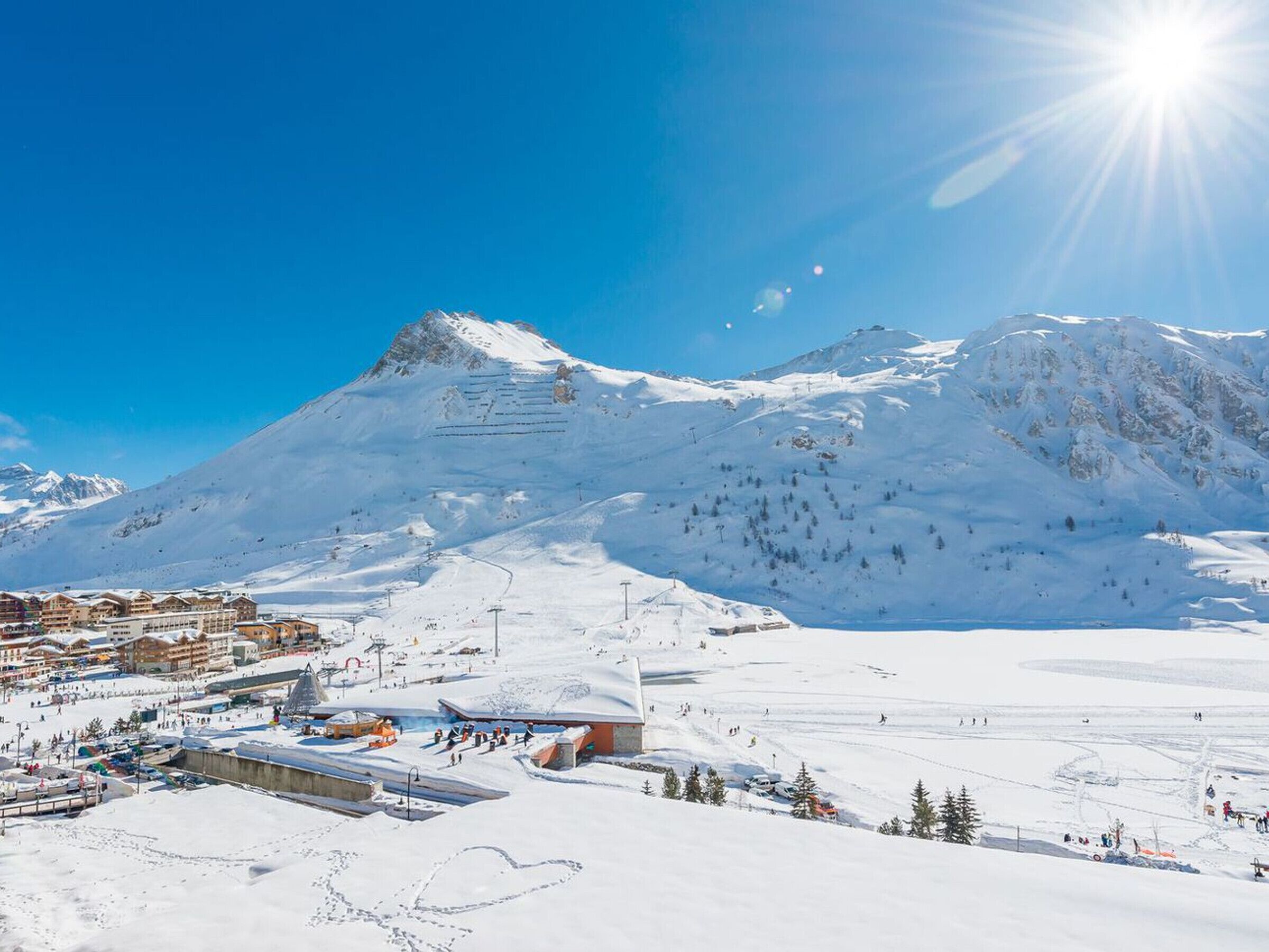 A snow-covered mountain with a ski resort, including buildings and ski lifts.