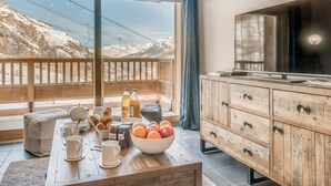 Ein Zimmer mit einem Holzespeisetisch, gedeckt mit Frühstücksleckereien, einer Obstschale und einem Fernseher auf einer Holzkommode.