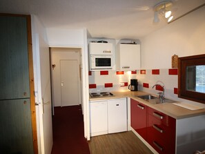 A compact kitchen with a microwave, stove, sink, and red cabinets. - Spacious Apartment in Tignes-Le Lavachet (Tignes-Le Lavachet)
