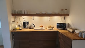 A kitchen with wooden cabinets, a coffee maker, a kettle, and jars on the counter. - Tokeryds Herrgård (Jonkoping)