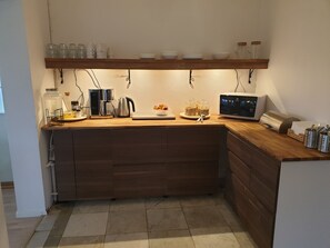 Eine Küche mit Holdekor, einer Kaffeemaschine, einem Wasserkocher und Gläsern auf der Arbeitsfläche.