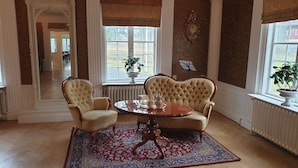 A room with two upholstered chairs, a wooden table, and a patterned rug. - Tokeryds Herrgård (Jonkoping)