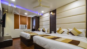 A hotel room with two beds, a ceiling fan, recessed lighting, a TV, and an air conditioning unit. - Hotel Atlantica Ajmer (Ajmer)