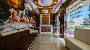 A lobby with a reception desk, a brown sofa, a white sofa, and a mural of horses. - Hotel Atlantica Ajmer (Ajmer)