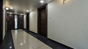 A hallway with a tiled floor, dark wooden doors, and recessed ceiling lights. - Hotel Atlantica Ajmer (Ajmer)