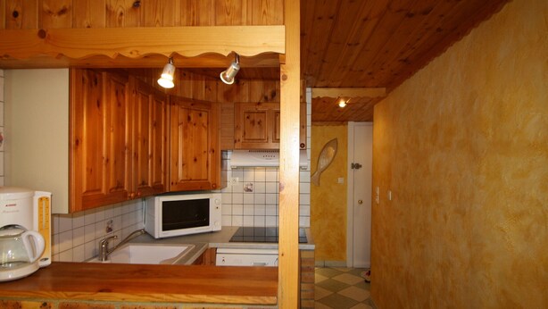 A kitchen with wooden cabinets, a microwave, a coffee maker, and a tiled backsplash.
