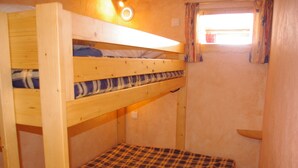 A bunk bed room with a window and a small shelf.