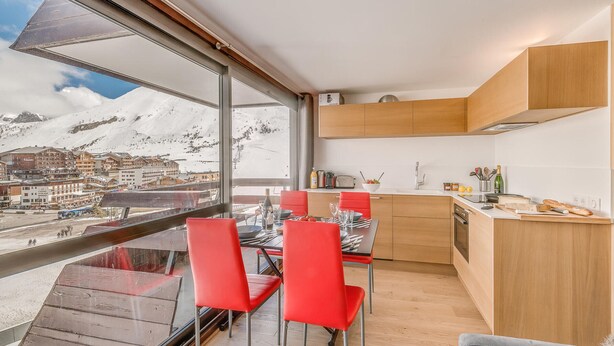 Eine moderne Küche mit Holzschränken und einem großen Fenster mit Blick auf eine verschneite Bergstadt.