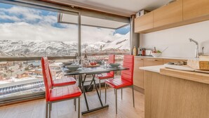 Eine moderne Küche mit einem großen Fenster mit Blick auf eine verschneite Berglandschaft.