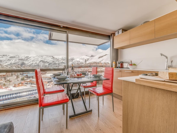 A modern kitchen with a large window overlooking a snowy mountain landscape.
