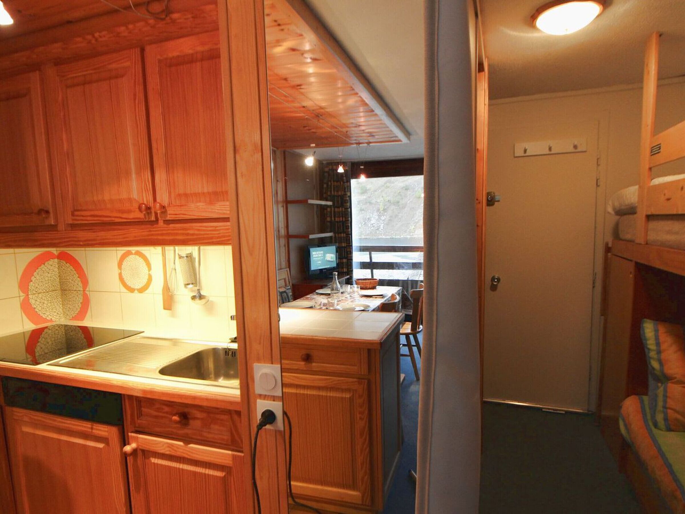 Una cocina compacta con armarios de madera, un lavamanos y una zona de comedor con mesa y sillas.