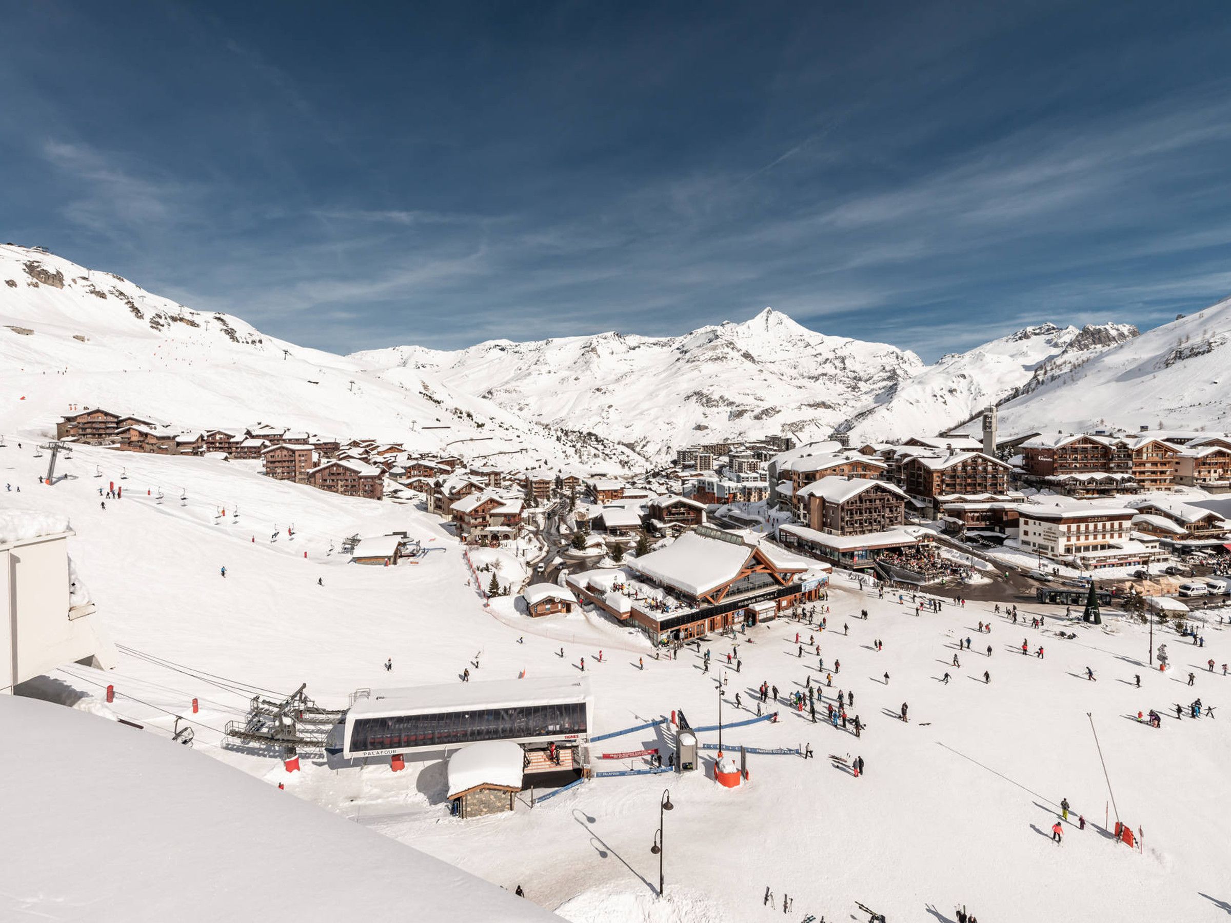 A snow-covered mountain town with ski slopes, buildings, and a clear sky.