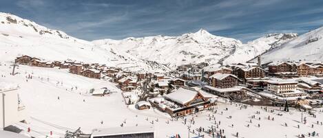 A snow-covered mountain town with ski slopes, buildings, and a clear sky.