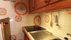 A kitchen with a stainless steel sink, wooden cabinets, and decorative orange and white tiles. - Large studio for 4 ppl. with balcony and lake view in Tignes (Tignes)