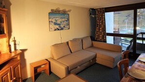 A cozy living room with a sofa, a small table, and a window with curtains. - Large studio for 4 ppl. with balcony and lake view in Tignes (Tignes)