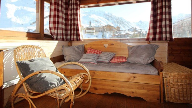 A cozy wooden cabin with a bed, a wicker chair, and a view of snow-covered mountains. - Traditional Chalet in Tignes - 3 rooms, 6 people, WiFi included (Tignes)