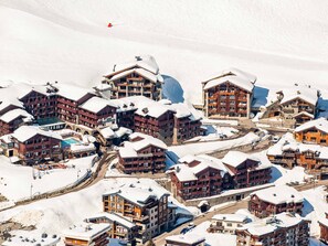 A snow-covered mountain resort with multiple wooden buildings, including lodges and a hotel.