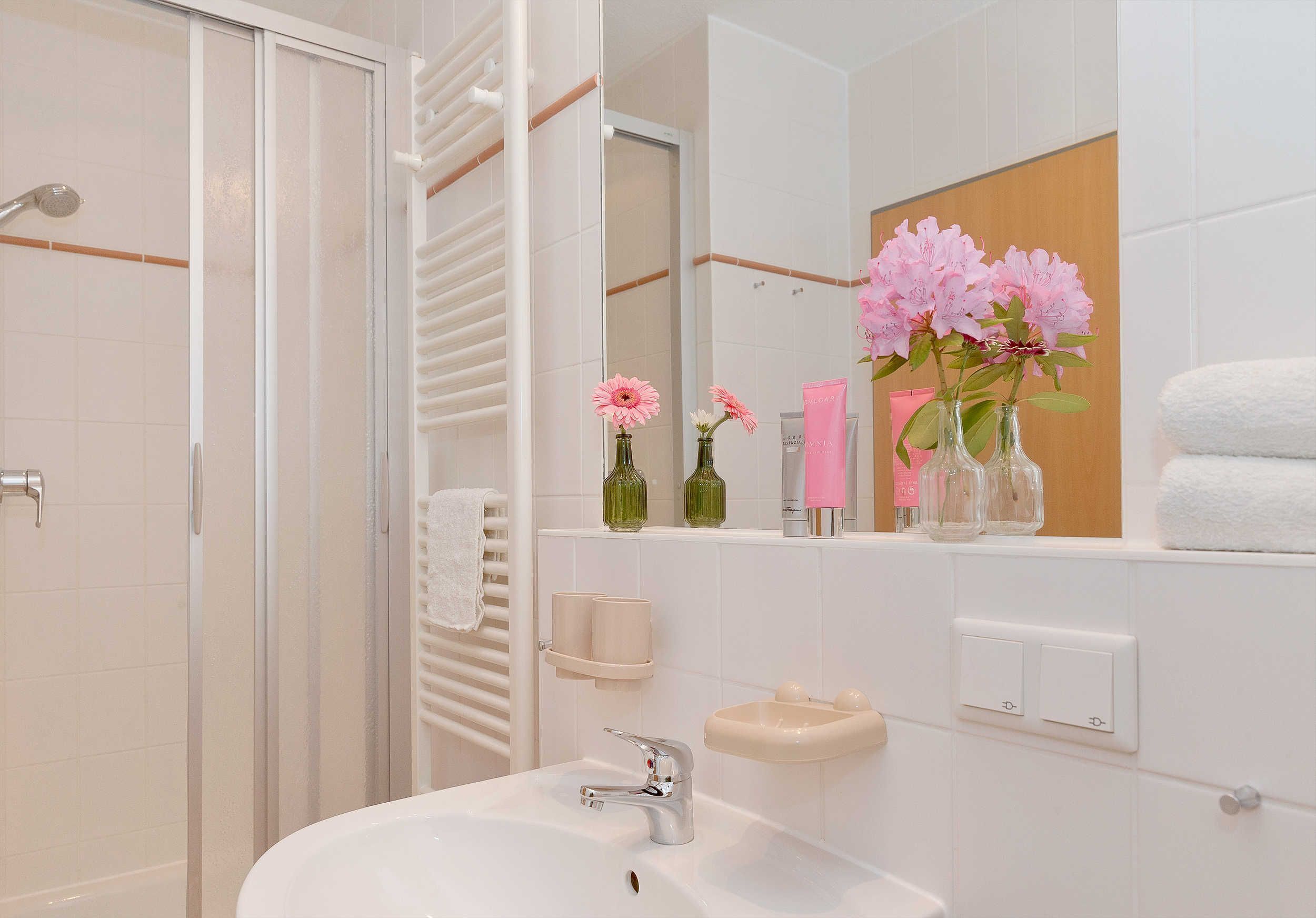 Une salle de bain moderne avec une douche à parois de verre, un lavabo blanc et un meuble-lavabo avec un miroir.