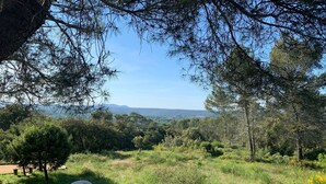 A terrace with two white plastic chairs and a table, overlooking a lush landscape with trees and distant hills. - Villa with panoramic view and huge pool (Saint-Siffret)