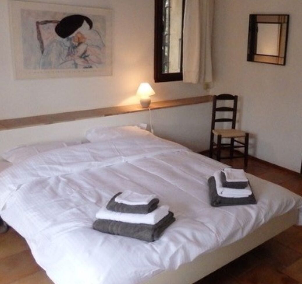 Ein ordentlich bezogenes Bett mit weißen Leinentüchern und zwei gefalteten Handtüchern.