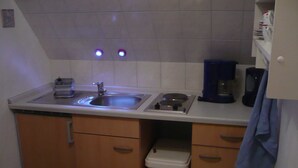 Una cocina compacta con un fregadero, estufa y un cubo de basura.