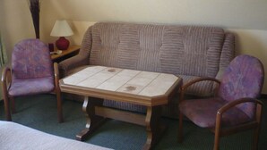Habitación con sofá, dos sillones, una mesita, lámpara y un florero.