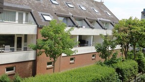 A multi-story building with a brick facade, multiple balconies, and a tower-like structure on the roof. - App Kapitänsstube, Germany (Sylt)